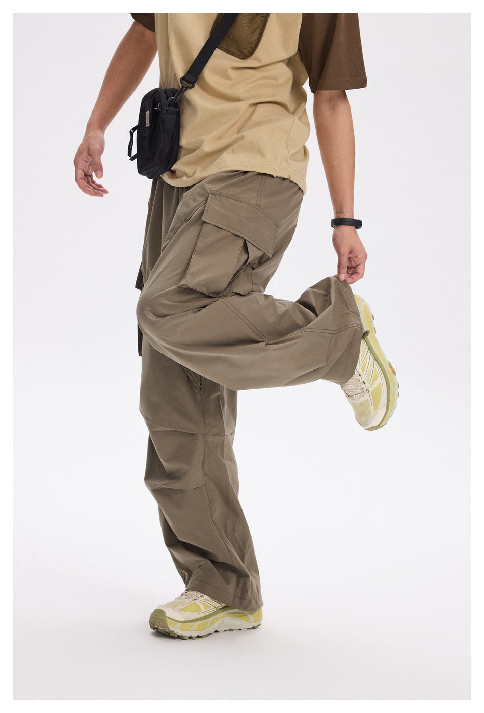 Cropped view of a model wearing taupe cargo pants with a large flap pocket and a tan-and-brown shirt.