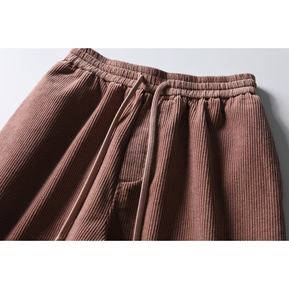 Close-up of dusty rose corduroy pants showing the elastic drawstring waist and front pleats.