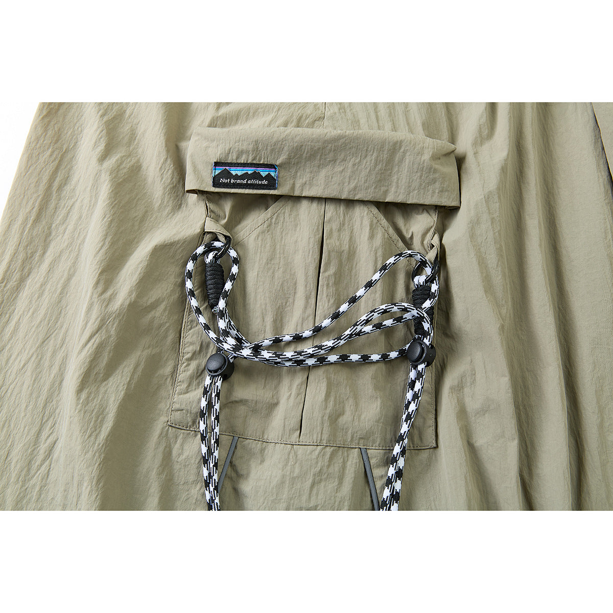 Close-up of a khaki skirt cargo pocket with a flap, black-and-white cord loops, and a small sewn label.