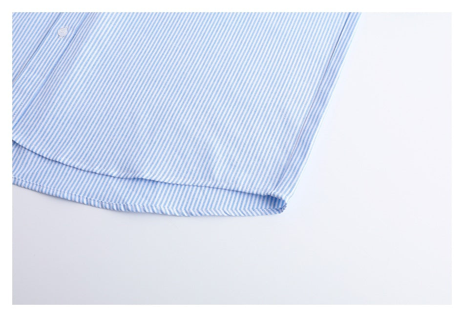 Close-up of a white shirt with fine blue vertical stripes, showing a button and curved hem.