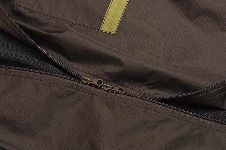 Close-up of a dark jacket's double zipper, mesh lining, and yellow fabric tab.