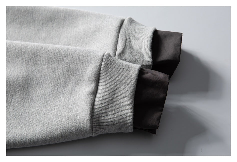 Close-up of light gray ribbed sweatshirt cuffs layered over dark fabric.