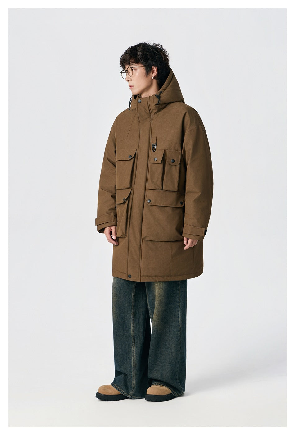 Model wearing brown longline hooded jacket with flap pockets, side view, with wide-leg jeans and suede boots
