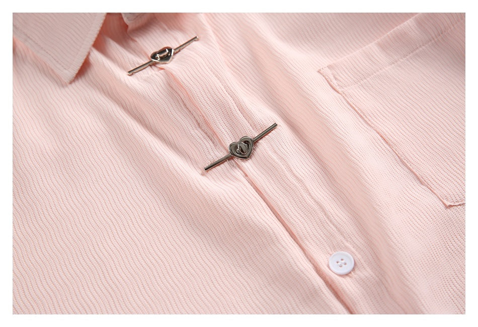 Close-up of a pale pink ribbed collared garment with metal toggle fasteners, a white button, and a pocket.