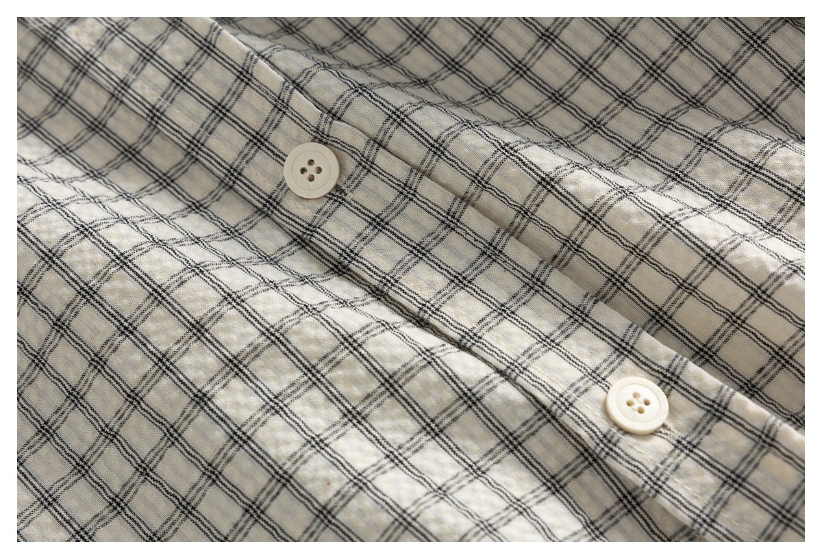 Close-up of the ivory shirt's black-plaid fabric and cream buttons along the front placket.
