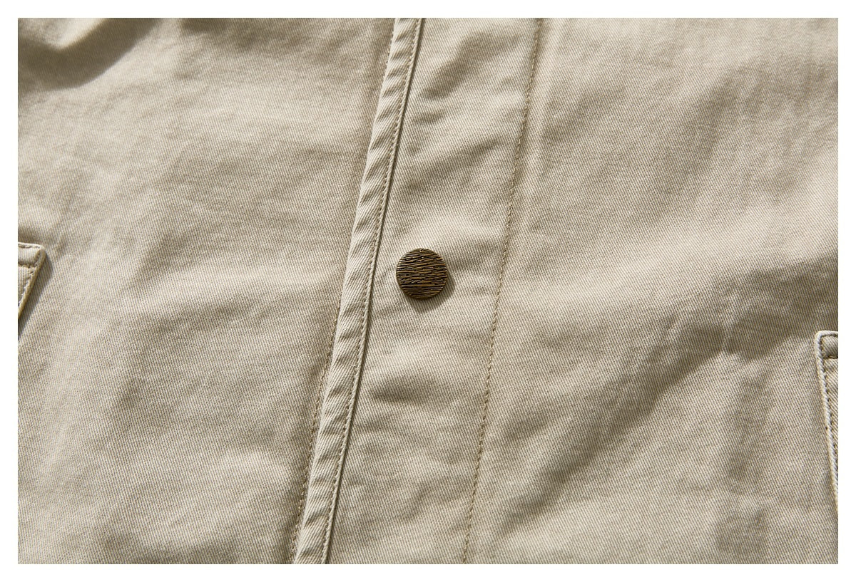 Close-up of a textured button and stitched placket on the beige jacket.