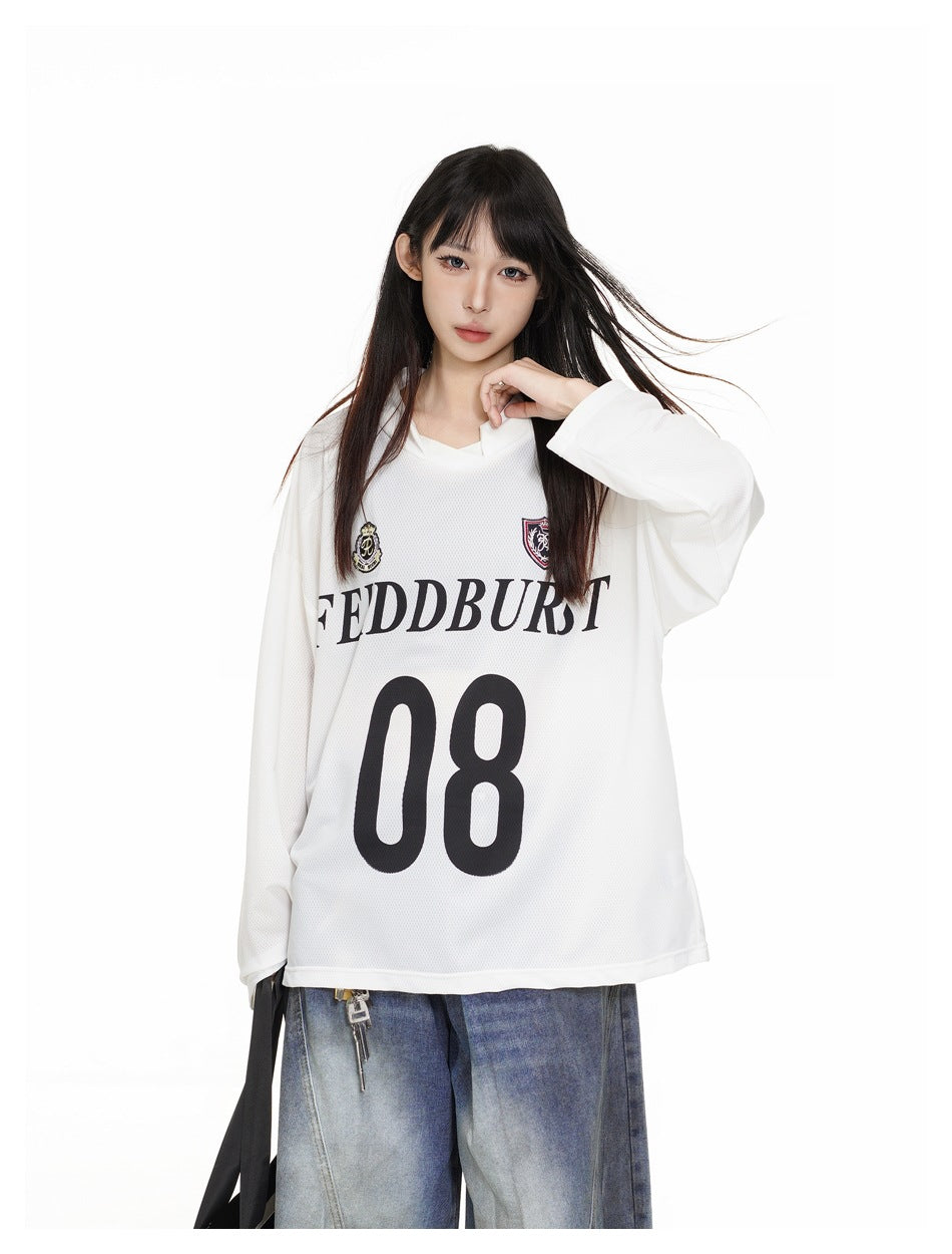 Model wearing an oversized white long-sleeve jersey with crest graphics, dark lettering and a large 08 on the front.