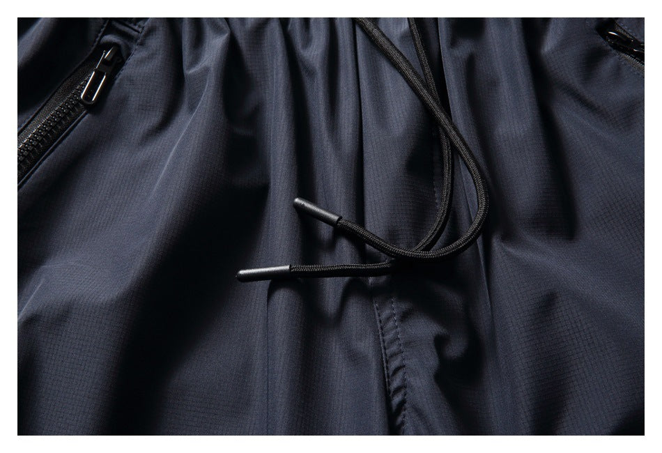 Close-up of navy pants showing the black waist drawcords and zipper pocket details.