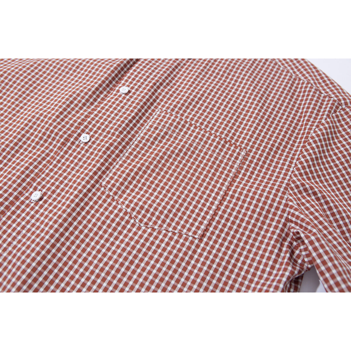 Close-up of the rust and white gingham shirt’s front button placket and single chest pocket.
