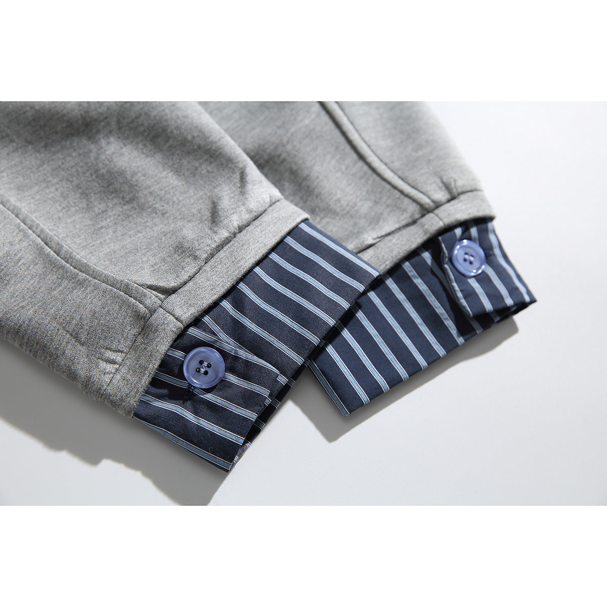 Close-up of the gray jacket's cuff, showing dark striped lining and a blue button.