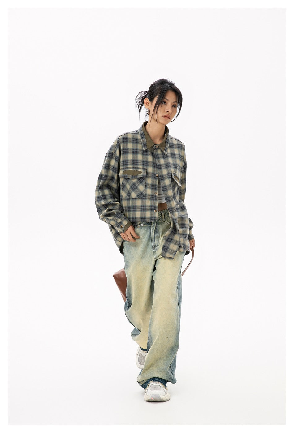 Model wearing an olive and blue plaid button-up shirt with distressed chest pockets and loose faded jeans.