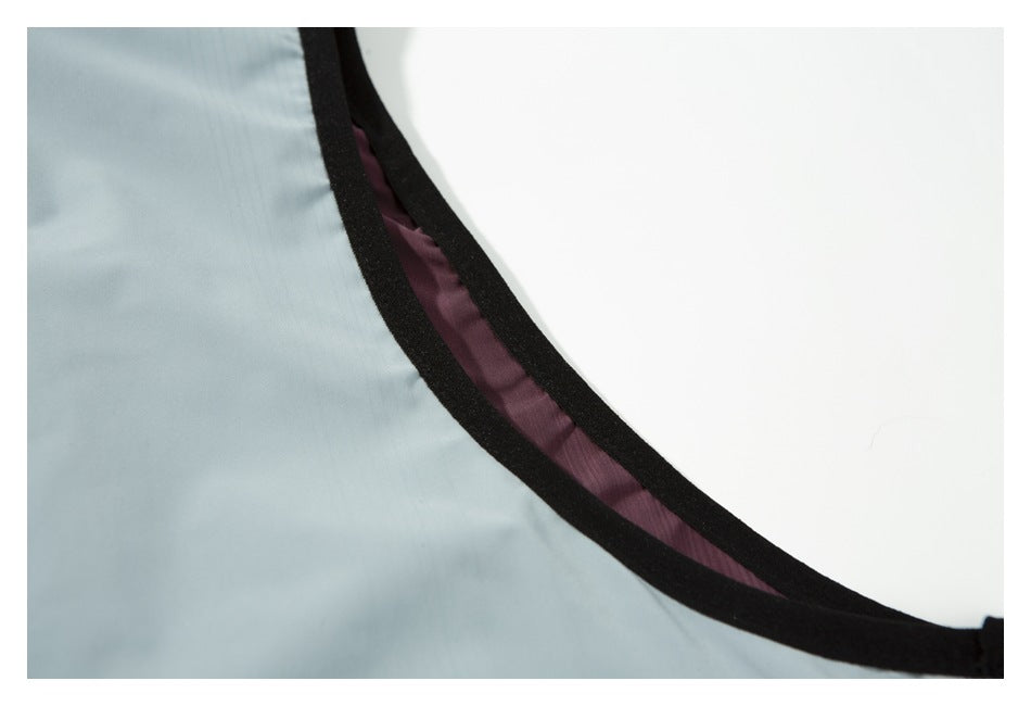 Close-up of the vest’s black-bound armhole edge with plum lining visible against pale gray fabric.