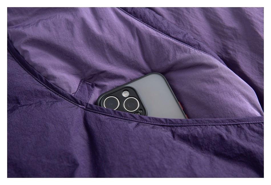 A phone sits in the large pocket of a purple jacket.