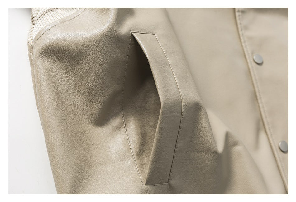 Close-up of a beige jacket's angled pocket, sleeve seam, and snap buttons.