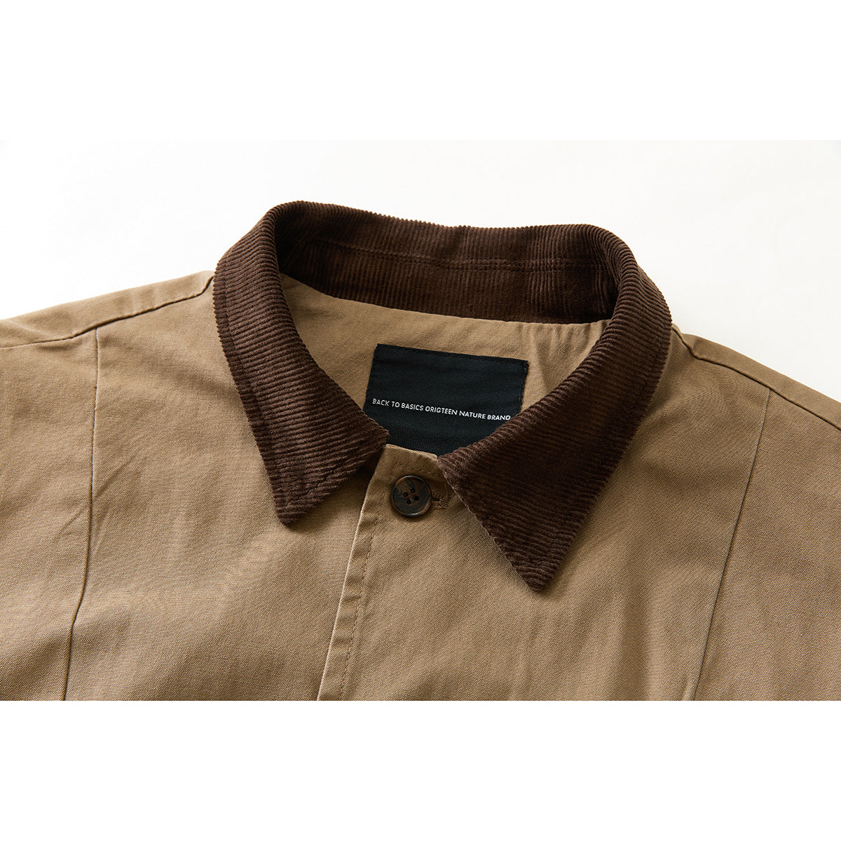 Close-up of a tan vest with a dark brown corduroy collar, button, and black neck label.