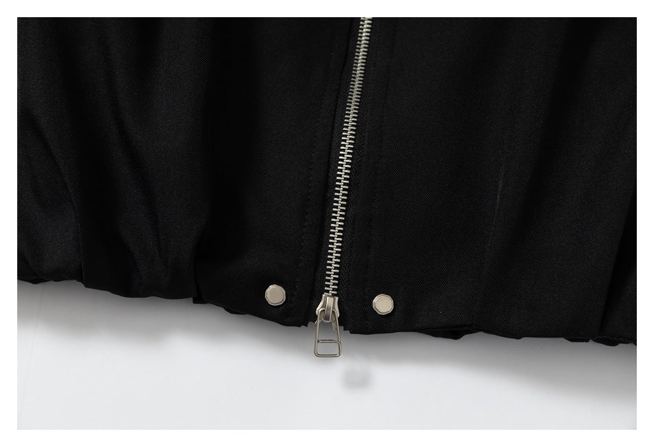 Close-up of a black garment hem with a silver zipper and two round metal snaps.