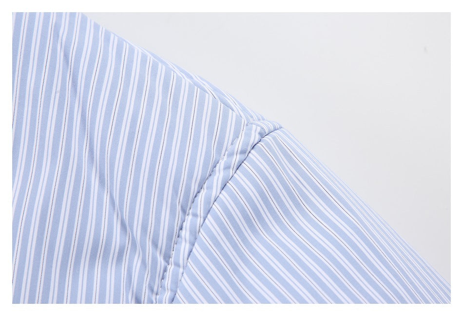 Close-up of the shoulder seam on a pale blue and white vertically striped shirt.