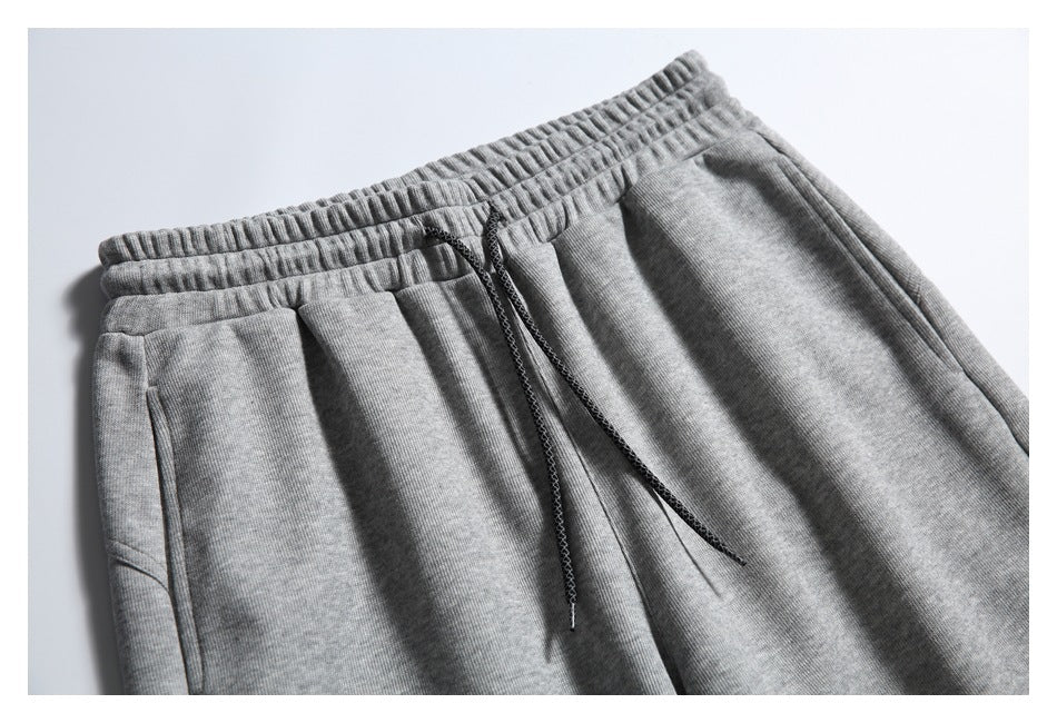 Close-up of gray jogger pants showing the elastic waistband, dark drawstring, and front pocket area.