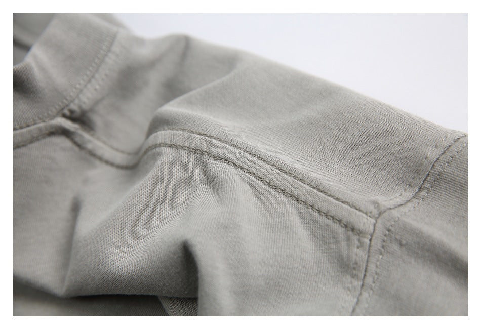 Close-up of shoulder and neckline stitching on a plain light gray garment.