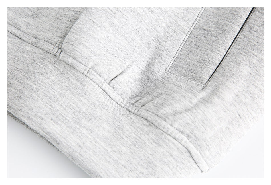 Close-up of light gray heathered garment fabric with stitched seams and a pocket edge.