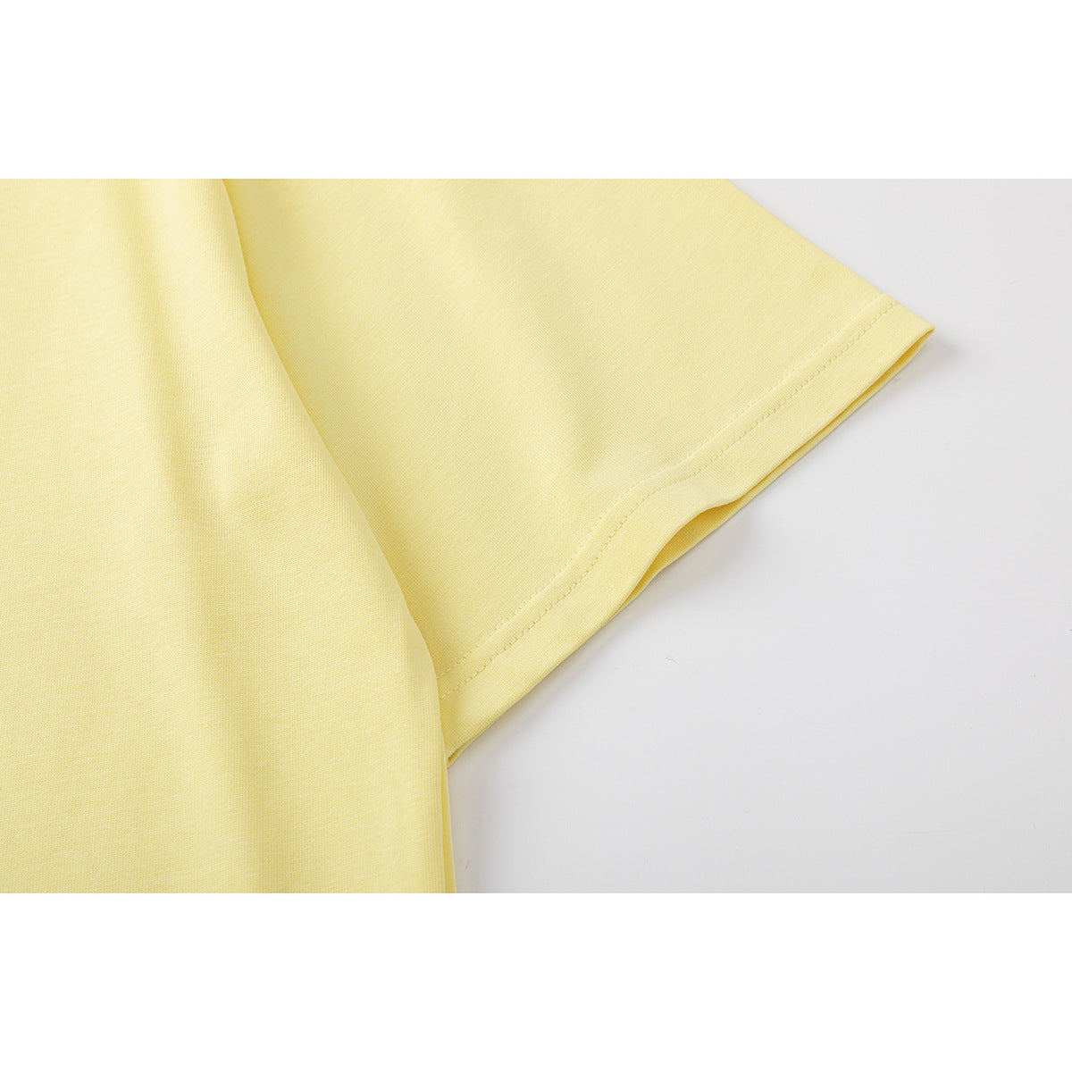 Close-up of the pale yellow T-shirt's short sleeve and stitched hem.