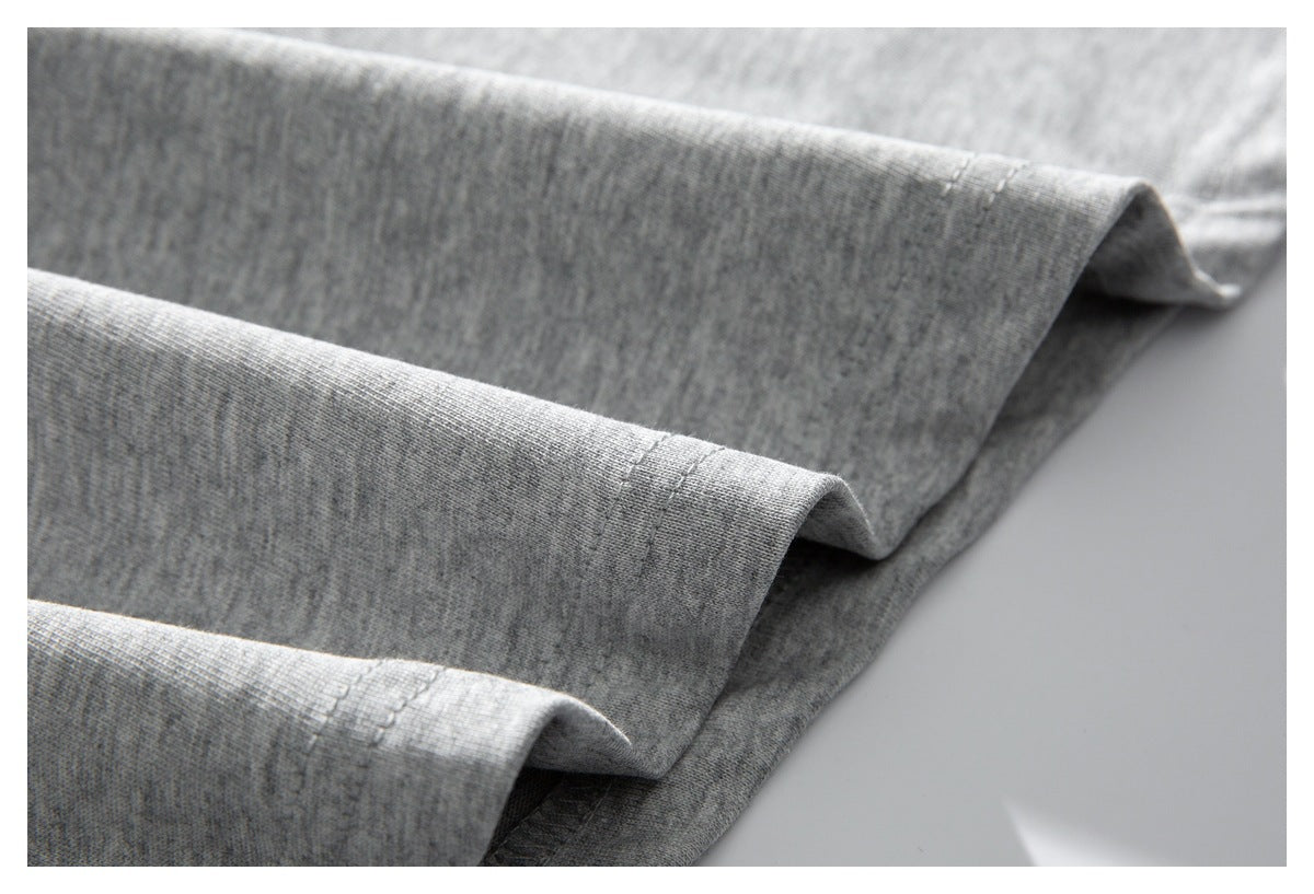 Close-up of the folded bottom hem and stitching on a light gray shirt.