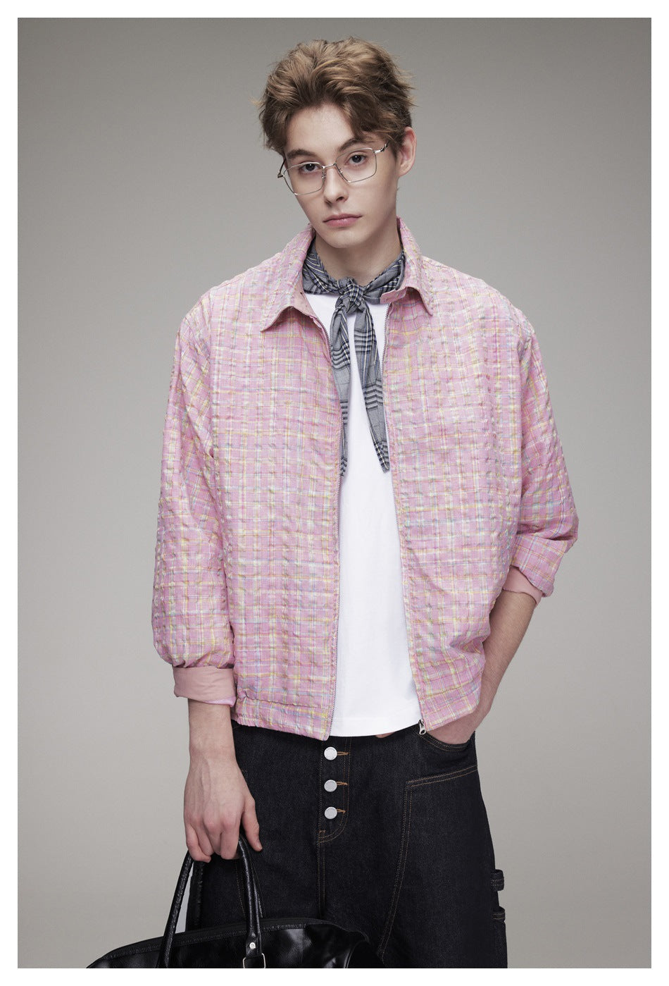 Close view of a model wearing a pink plaid jacket over a white shirt with a gray plaid neck scarf.