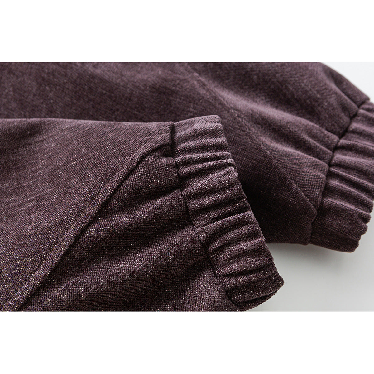 Close-up of a mauve-brown jacket sleeve with a gathered ribbed cuff and stitched panel details.