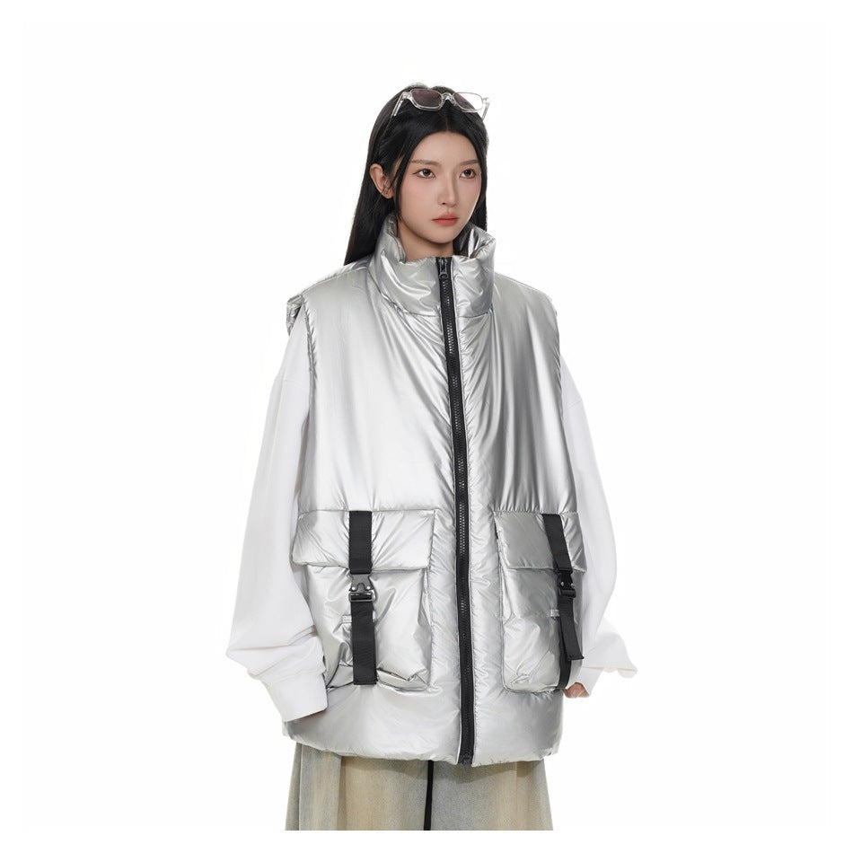 Model wearing a silver puffy stand-collar vest with buckle-strap pockets over a white top, front view