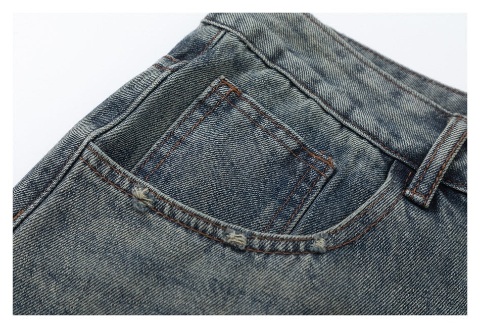 Close-up of a small front coin pocket and contrast stitching on faded blue jeans.