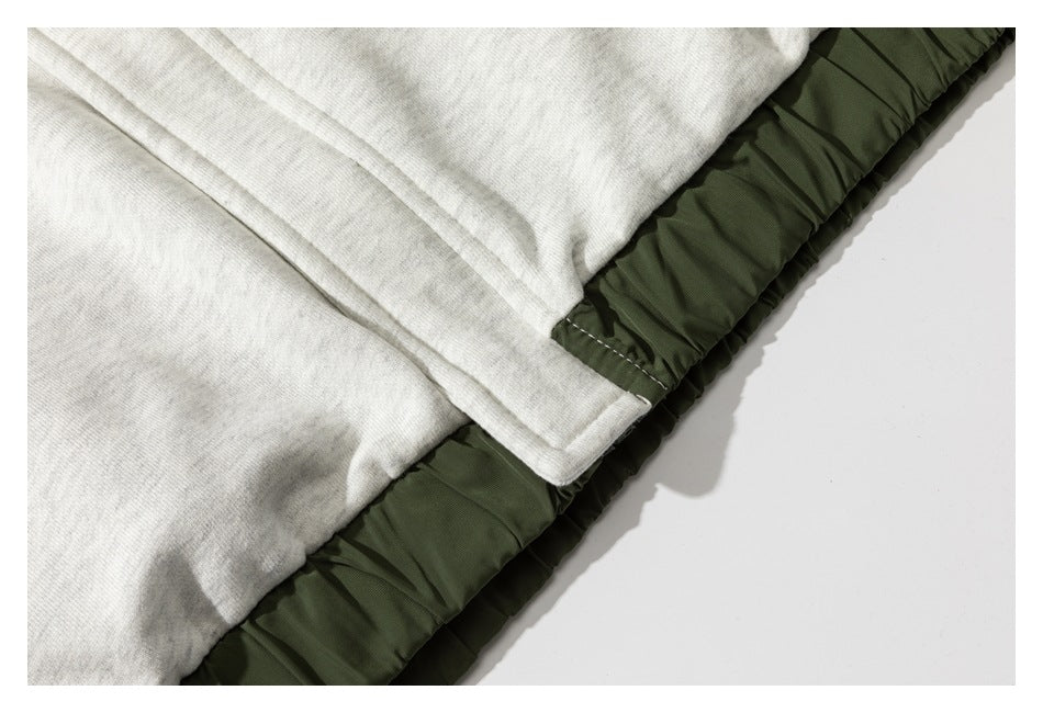 Close-up of light gray hoodie fabric meeting dark olive gathered material along a seam.