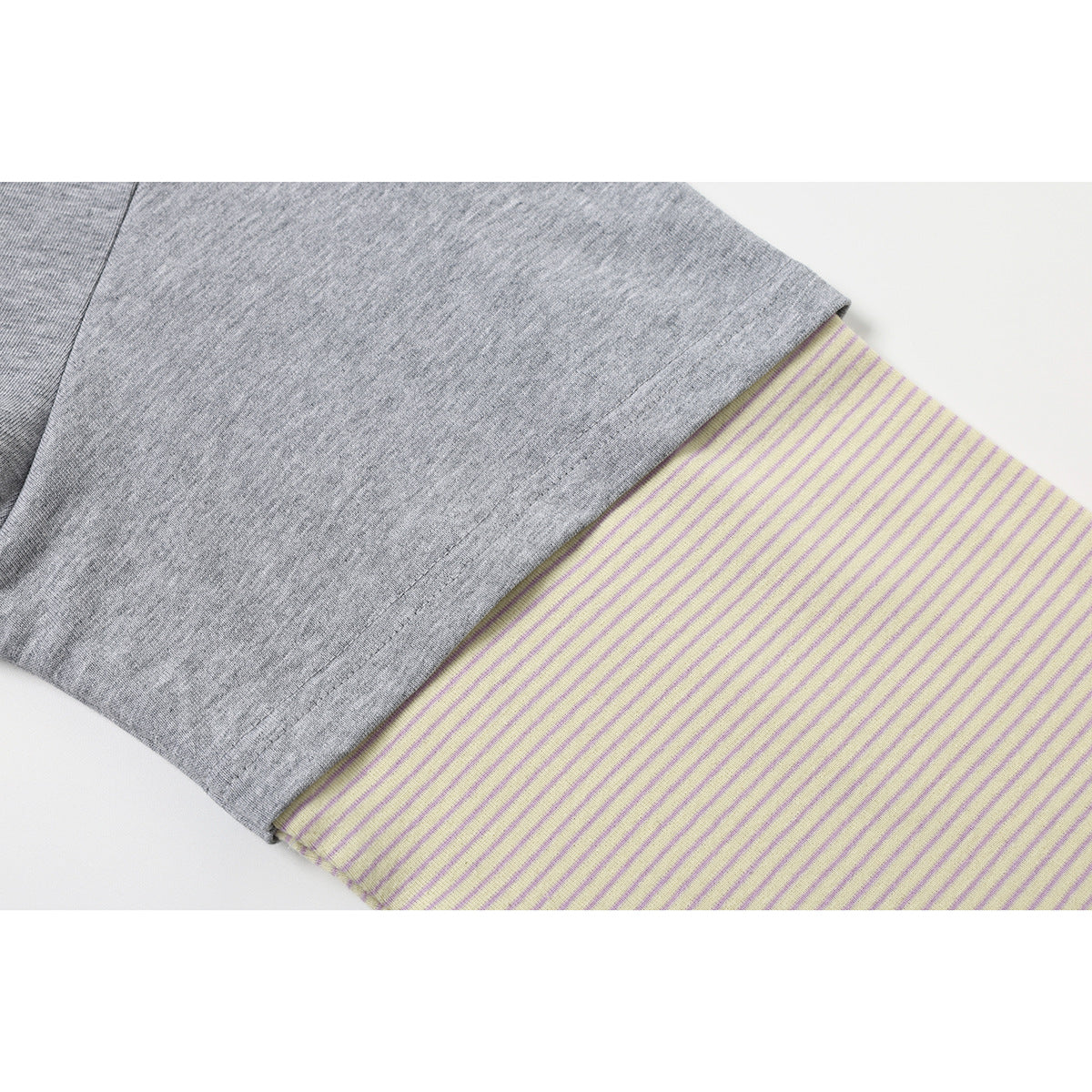Close-up of a gray short sleeve layered over a cream sleeve with thin lavender stripes.