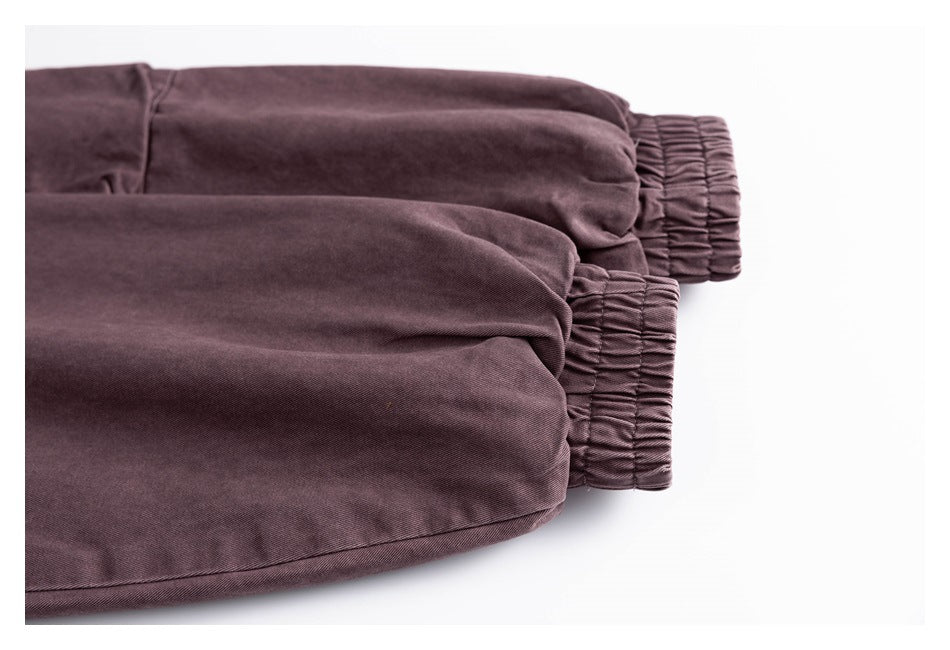 Close-up of two muted plum pant legs with gathered elastic cuffs.