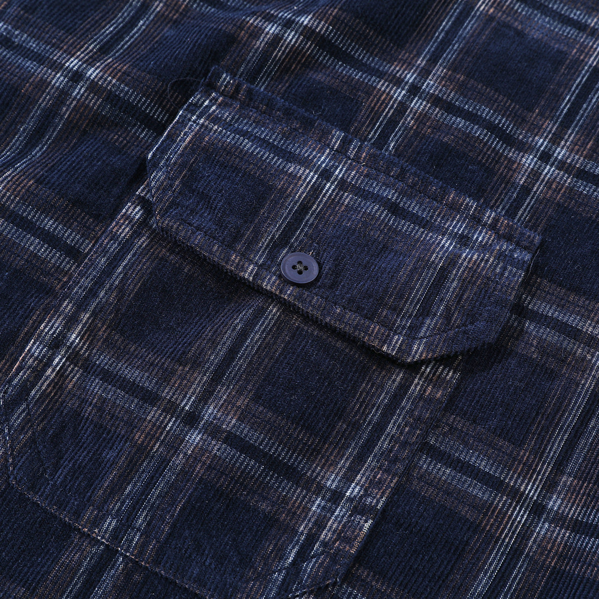 Close-up of a buttoned chest pocket on a dark navy plaid shirt.