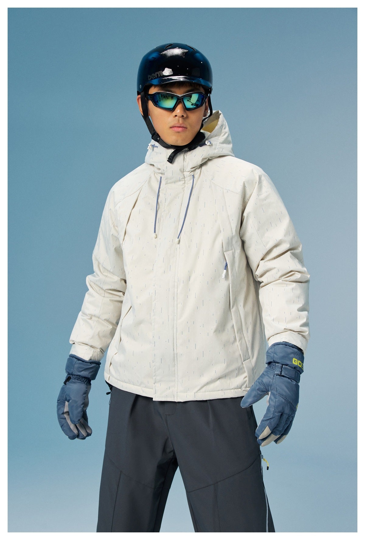 Model wearing a white patterned hooded ski jacket and blue gloves, shown from the front with helmet and goggles.