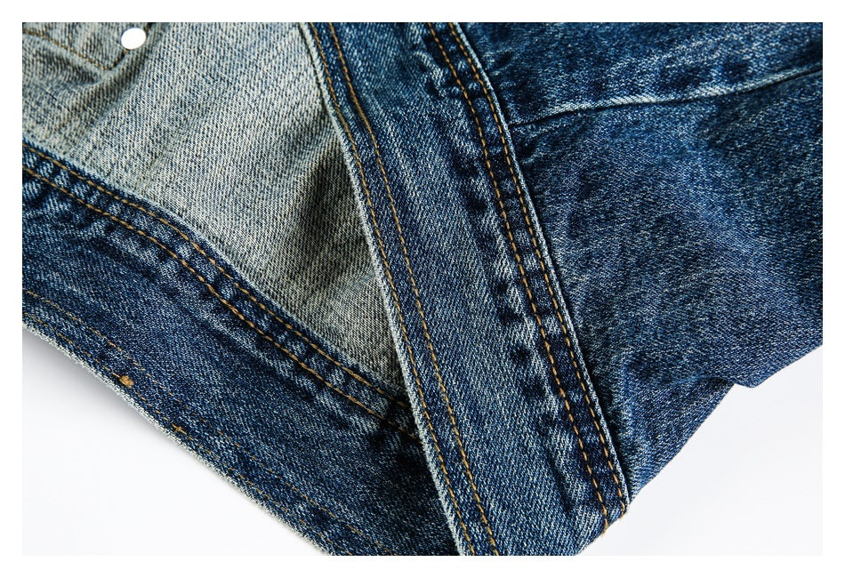 Close-up of overlapping blue denim panels with contrasting double-stitch seams and a metal snap.
