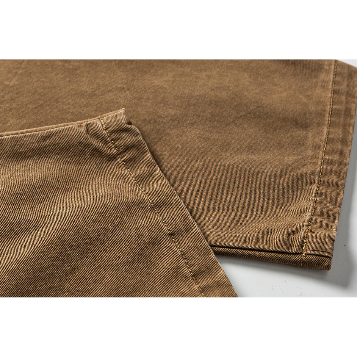 Close-up of tan pants fabric and stitched leg hems.