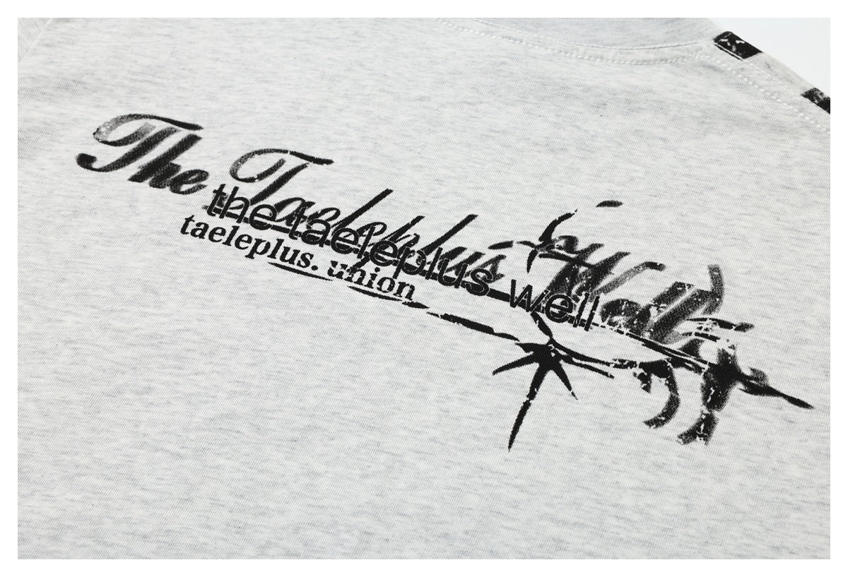 Close view of a black distressed text graphic printed across the back of a light heather gray T-shirt.