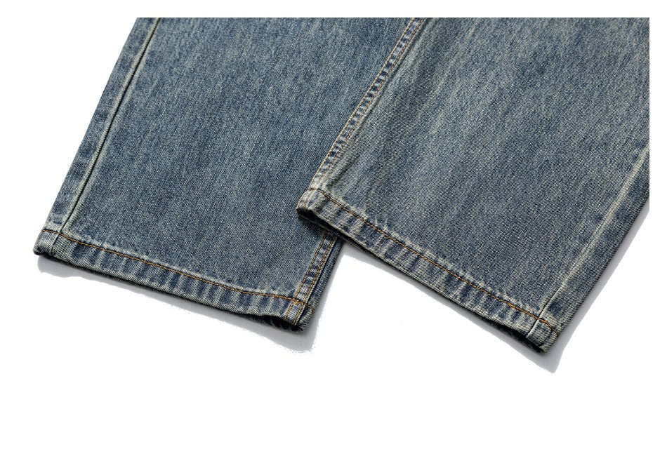 Close-up of blue faded denim jean hems with orange-brown stitching.