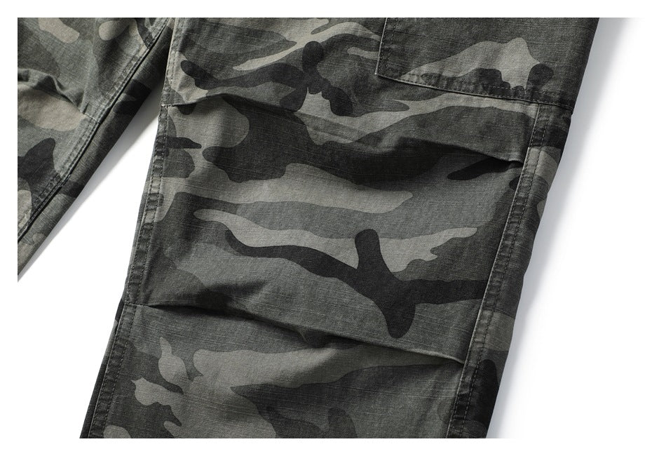 Close-up of a gray and black camouflage cargo trouser leg with a large stitched flap pocket.
