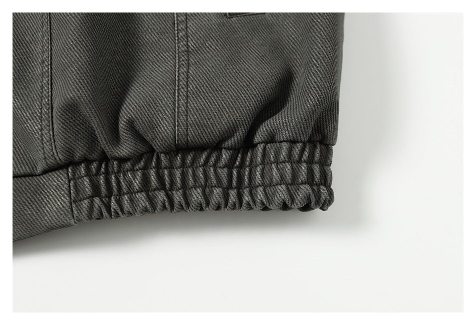 Close-up of the charcoal gray jacket's gathered elastic hem and stitched panel.