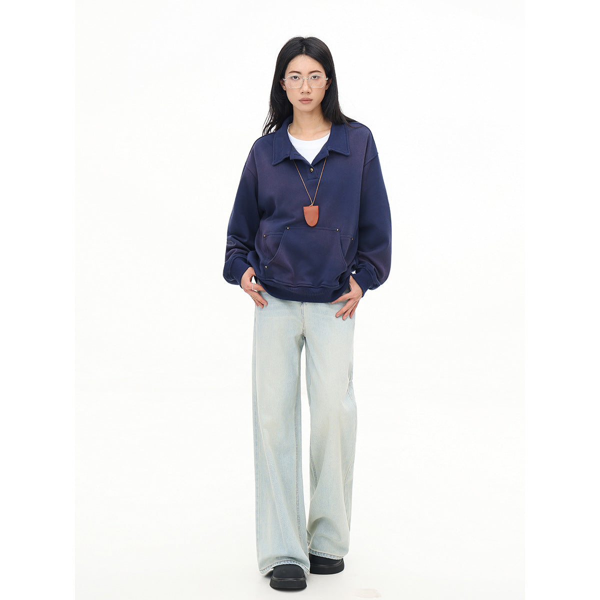 Model wearing an oversized navy collared pullover with a front pouch pocket and pale wide-leg jeans.