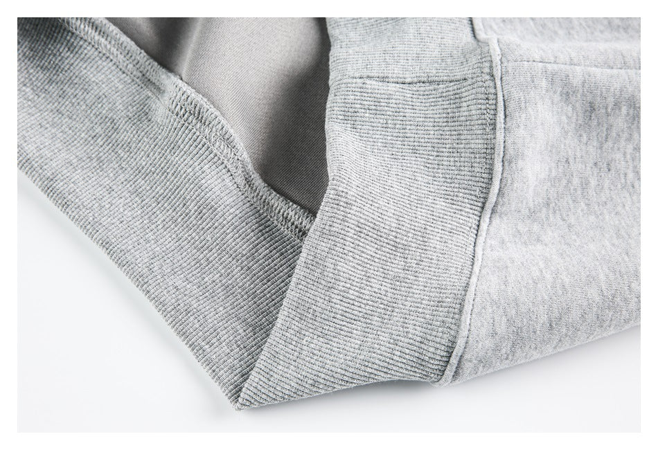 Close-up of ribbed sweatshirt trim and overlocked interior seam stitching in light gray.