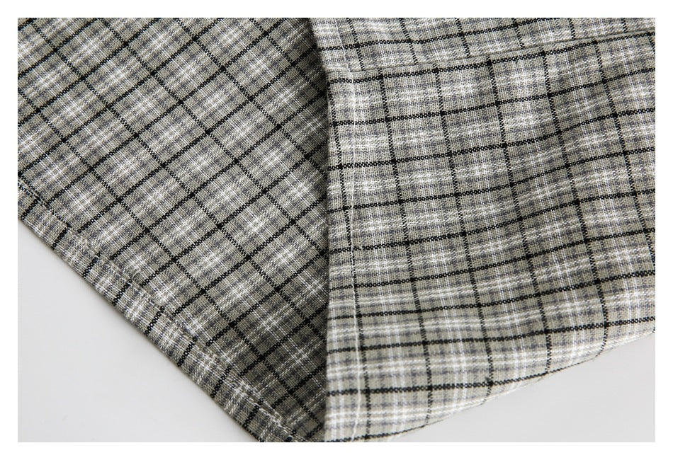 Close-up of gray and beige plaid fabric with black grid lines, folded to show both sides.