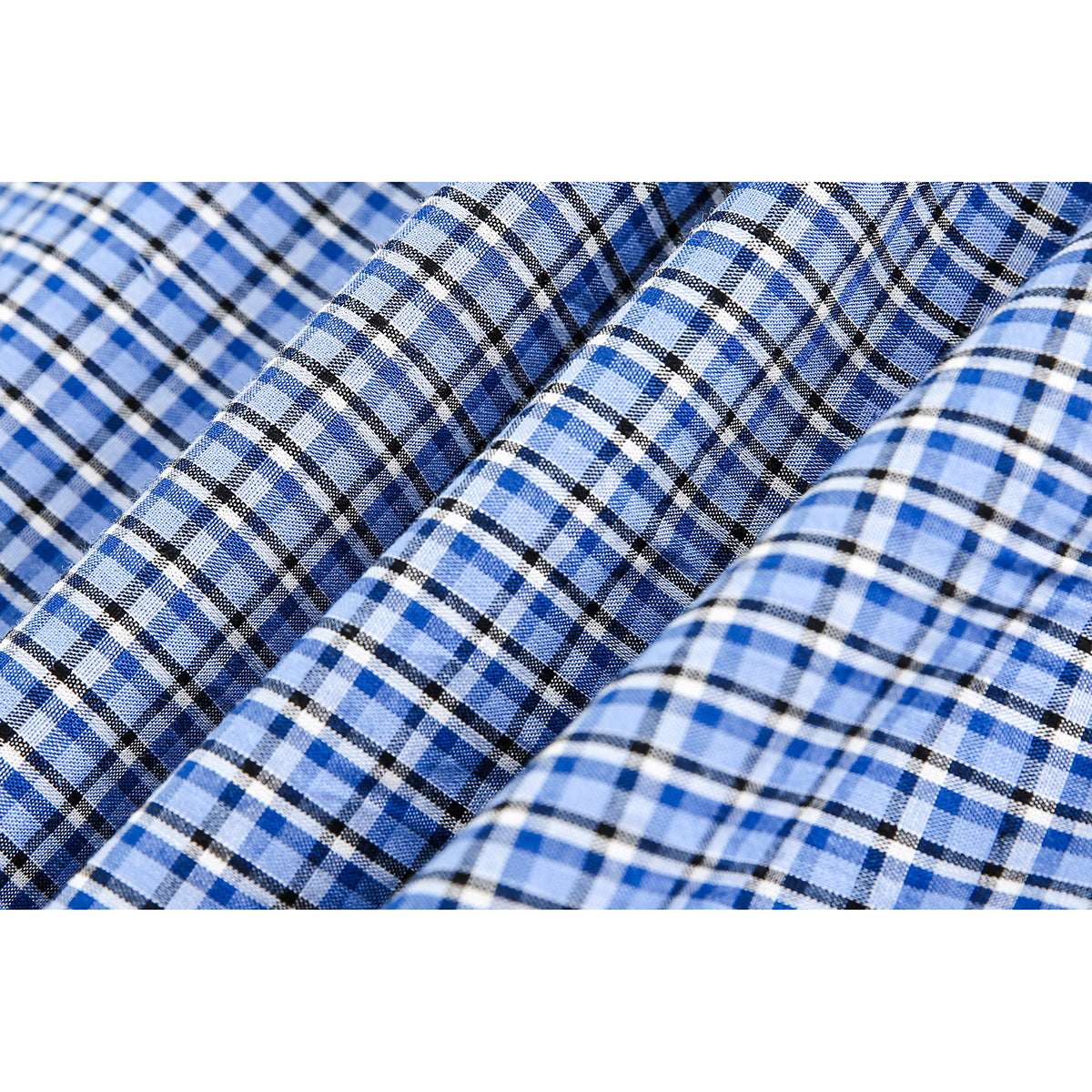 Close-up showing the blue, white and black plaid pattern and folds of the shirt fabric.