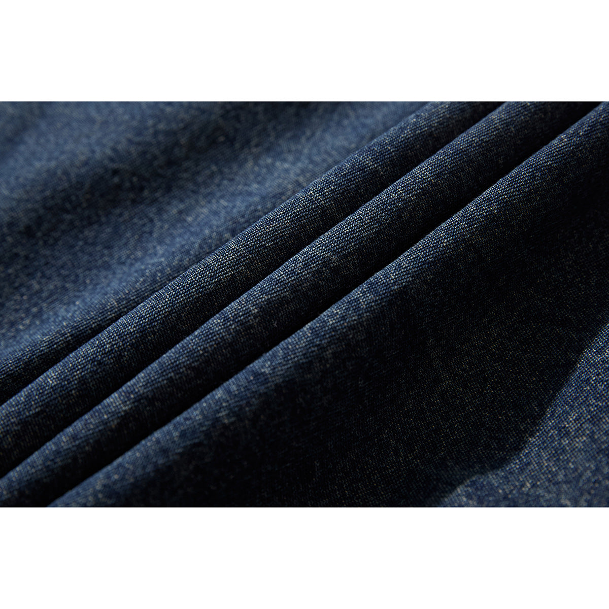 Macro view of dark blue denim fabric arranged in diagonal folds.