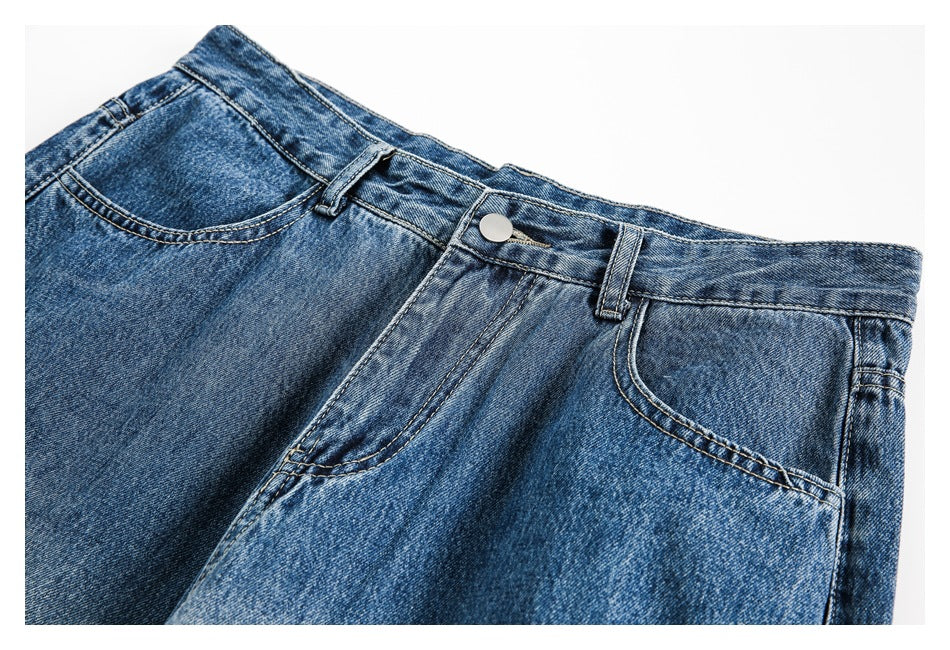 Close-up of the jeans' front waistband, button, belt loops, fly, and curved pockets in blue denim.