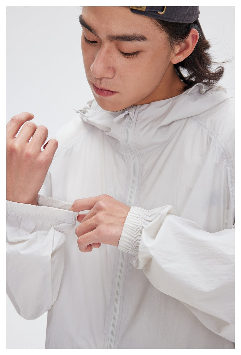 Close-up of the white jacket’s hood, front zipper, and elastic cuff and sleeve details.