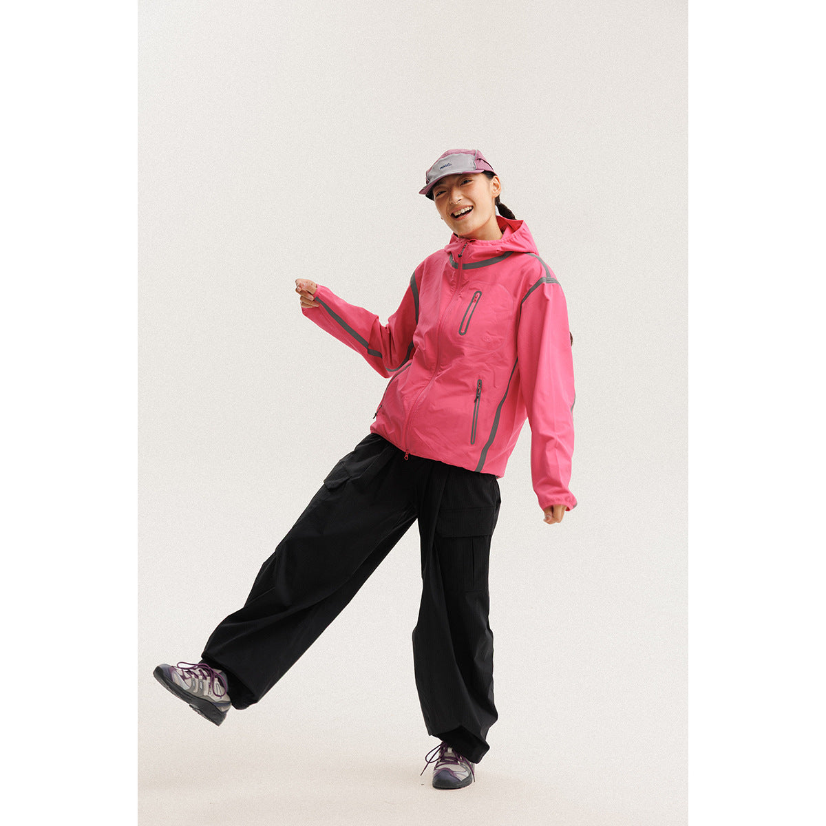 Woman wearing a bright pink hooded zip jacket with gray accents and black cargo pants.