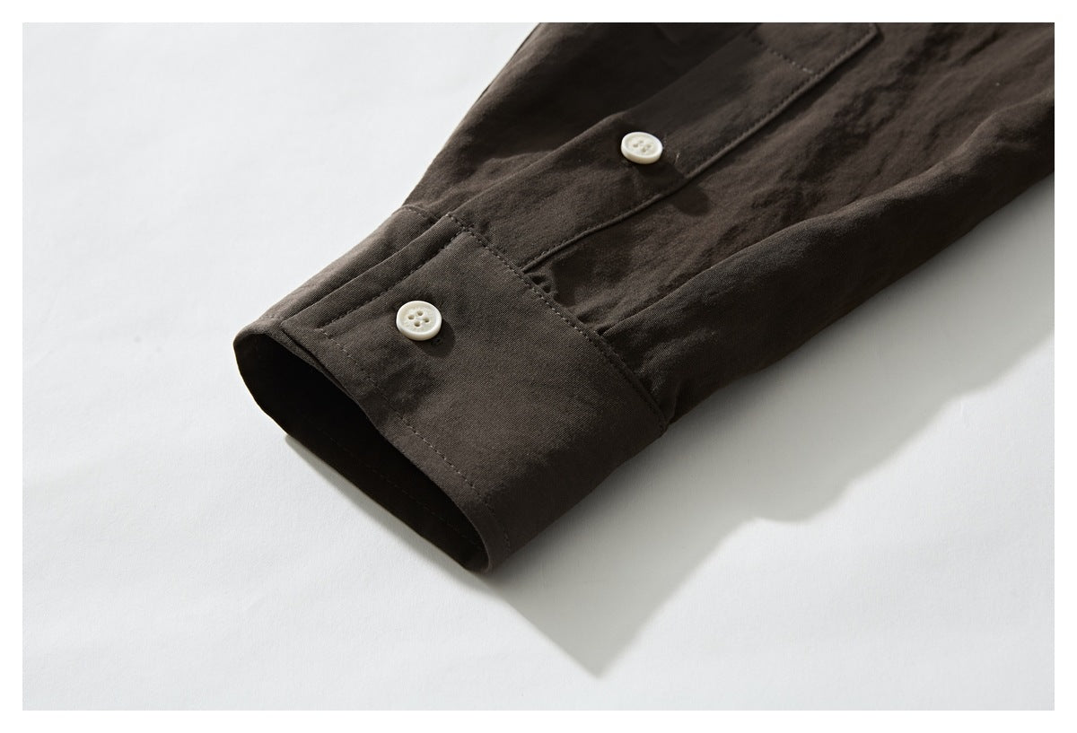 Close-up of a dark brown shirt sleeve cuff with two white buttons.